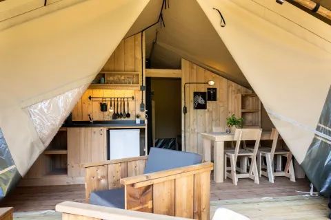 Interno di una tenda glamping safari al Campeggio Mareveld nei Paesi Bassi con cucina e mobili in legno.