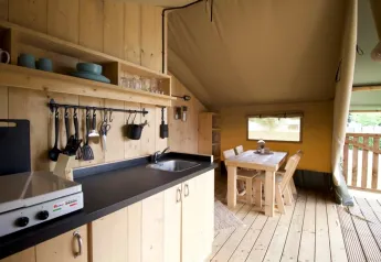 Cozy kitchen and dining area inside Glampingtent 4p safari tent at Campsite Mareveld in the Netherlands.
