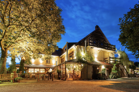 Evening view of Campsite Mareveld in Limburg, Netherlands, featuring a warmly lit building and outdoor seating.