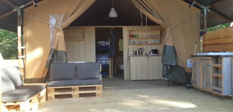 Innenraum eines Safarizeltes auf dem Campingplatz Moulin de Chaules in Frankreich mit Holzboden und Küchenzeile.