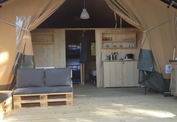 Safari teltinteriør på Camping Moulin de Chaules i Frankrig med trægulv, pallemøbler og tekøkken.
