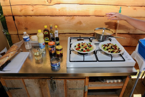 Udendørs køkken i en safaritelt på Camping Moulin de Chaules, Frankrig, med salater og ingredienser.