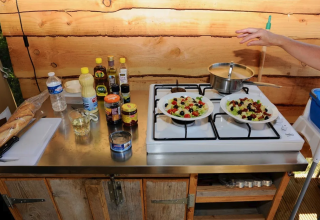 Outdoor kitchen in a safari tent at Camping Moulin de Chaules, France, showing salads and ingredients.