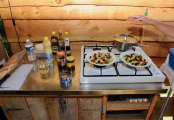 Udendørs køkken i en safaritelt på Camping Moulin de Chaules, Frankrig, med salater og ingredienser.