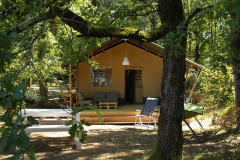 Tenda safari al Camping Moulin de Chaules in Francia, circondata da alberi e area relax esterna.