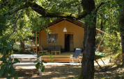 Safarizelt auf Camping Moulin de Chaules in Frankreich, umgeben von Bäumen mit Sitzgelegenheiten.