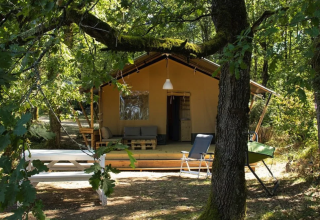 Tenda safari al Camping Moulin de Chaules in Francia, circondata da alberi e area relax esterna.