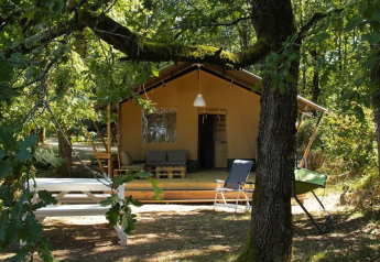 Tienda safari en Camping Moulin de Chaules en Francia, rodeada de árboles y zona de descanso exterior.