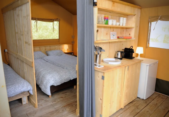 Vue intérieure de la tente safari au Camping Moulin de Chaules en France, avec chambre et coin cuisine.