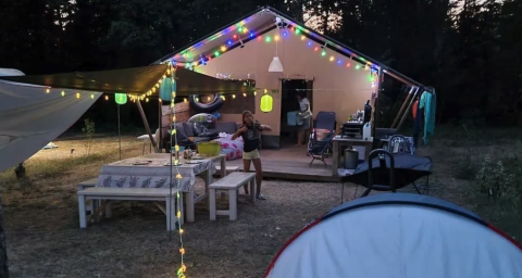 Tente safari décorée de guirlandes lumineuses colorées au Camping Moulin de Chaules, en France.