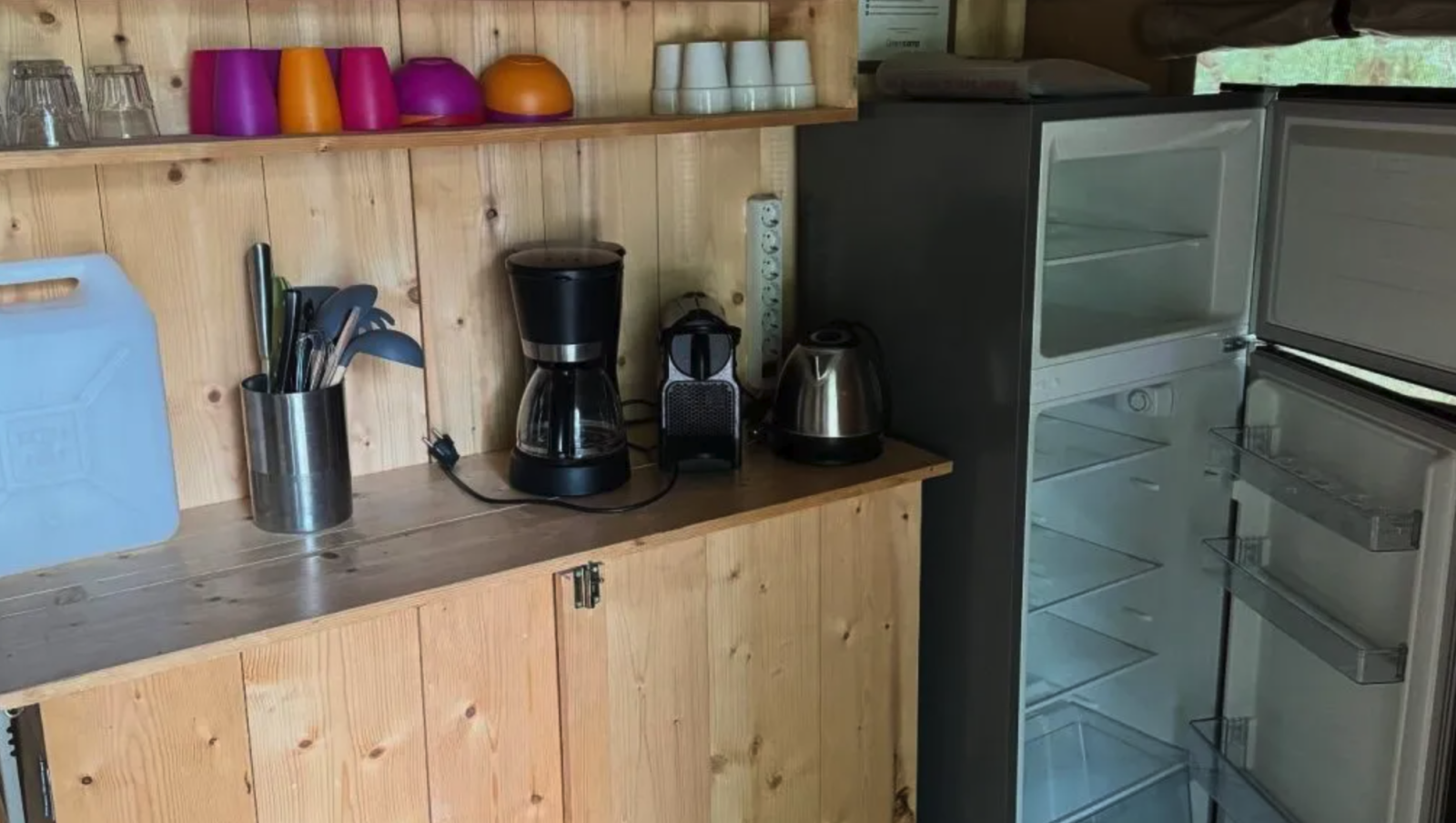 Keukenhoek in een safaritent op Camping Moulin de Chaules in Frankrijk met open koelkast en apparaten.