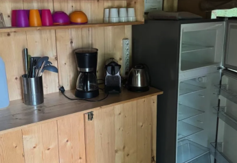 Kitchen area inside a safari tent at Camping Moulin de Chaules, France, featuring appliances and an open fridge.