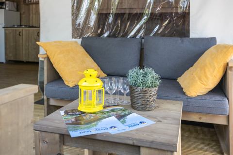 Divano grigio con cuscini gialli e tavolino in una tenda safari al Camping Aminess Maravea, Croazia.