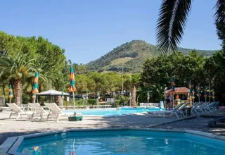Piscine extérieure avec transats et parasols au Camping Casa dei Prati en Toscane, Italie, avec vue sur les montagnes.