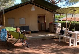 Ein Mädchen entspannt vor einem Safarizelt auf dem Campingplatz Casa dei Prati mit Sitzbereich in Italien.
