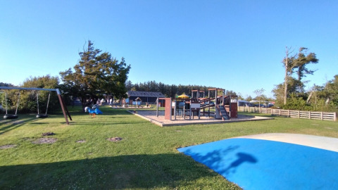 Parco giochi con altalene, scivoli e tappeto blu a Tornby Strand Camping, Jutland settentrionale, Danimarca.