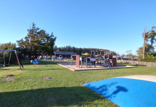 Speelplein met schommels, glijbaan en blauw speelvlak bij Tornby Strand Camping, Noord-Jutland, Denemarken.