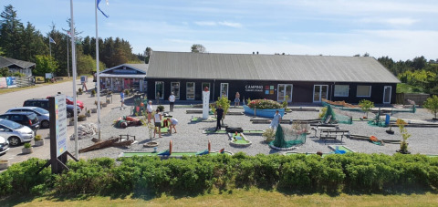 Famiglie giocano a minigolf al Tornby Strand Camping nel Nord Jutland, Danimarca, in una giornata di sole.