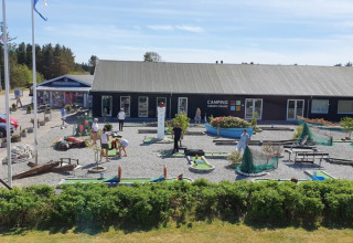 Gezinnen spelen minigolf bij Tornby Strand Camping in Noord-Jutland, Denemarken, op een zonnige dag.