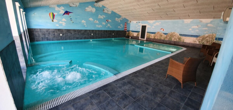 Binnenzwembad met jacuzzi en strandmuurschildering bij Tornby Strand Camping, Noord-Jutland, Denemarken.