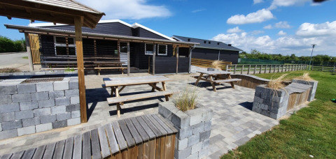 Zona exterior en Tornby Strand Camping, Jutlandia del Norte, Dinamarca, con bancos, mesas y muros de piedra.