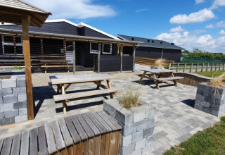 Zona exterior en Tornby Strand Camping, Jutlandia del Norte, Dinamarca, con bancos, mesas y muros de piedra.