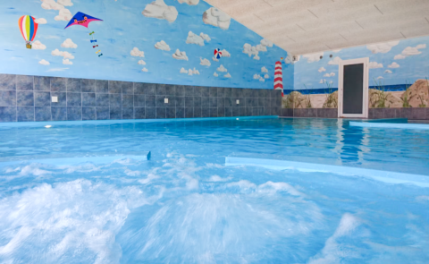 Piscina cubierta con mural de cielo y playa en Tornby Strand Camping, parque vacacional en Jutlandia del Norte, Dinamarca.