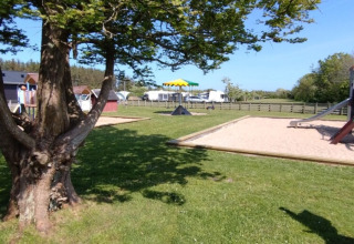 Área de juegos infantiles y césped en Tornby Strand Camping en Jutlandia del Norte, Dinamarca, día soleado.