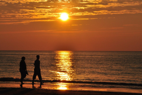 Dos personas pasean por la orilla en Tornby Strand Camping en North Jutland, Dinamarca, al atardecer.