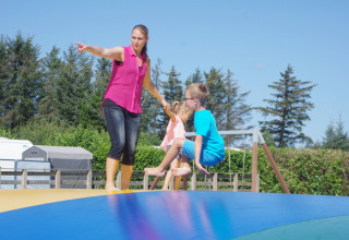 Mujer y dos niños juegan en un cojín inflable en Tornby Strand Camping, parque de vacaciones en Jutlandia del Norte.