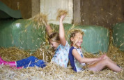 Dos niños juegan felices con paja en Landrijk de Reesprong, un parque vacacional en Overijssel, Países Bajos.