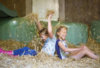 Zwei Kinder spielen fröhlich im Heu im Ferienpark Landrijk de Reesprong in Overijssel, Niederlande.