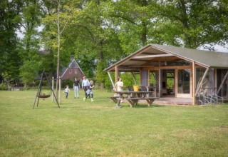 Famiglia si gode il tempo all’aperto davanti a una baita al Landrijk de Reesprong, parco vacanze in Overijssel.