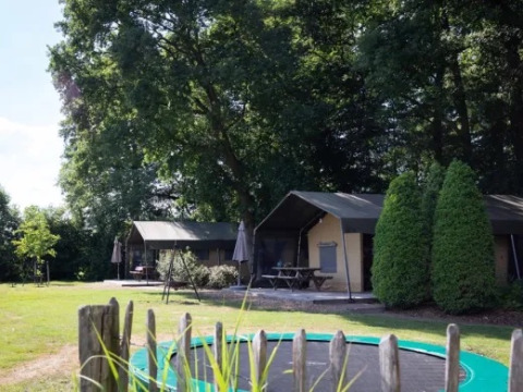Blick auf Landrijk de Reesprong Ferienpark mit Lodges, Trampolin und Bäumen in Overijssel, Niederlande.