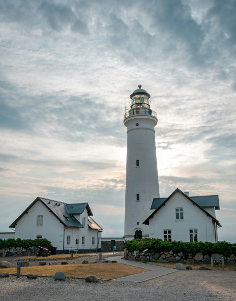 Lighthouse and white houses under a cloudy sky near Hirtshals in North Jutland, Denmark.