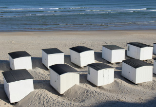 Cabanes de plage blanches avec toits noirs à Tornby Strand Camping, Jutland du Nord, Danemark.