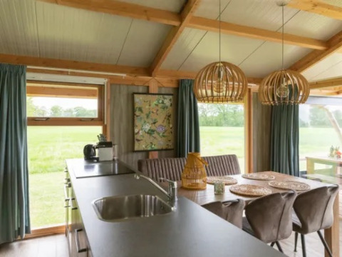 Vista interna del Welness Luxe lodge a Landrijk de Reesprong nei Paesi Bassi, con cucina e zona pranzo.