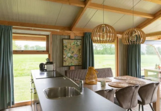 Innenaufnahme der Welness Luxe Lodge in Landrijk de Reesprong, Niederlande, mit Küche und Esstisch.
