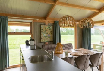 Vue intérieure du Welness Luxe lodge à Landrijk de Reesprong, Pays-Bas, avec cuisine et salle à manger.