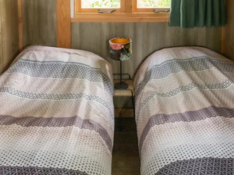 Letti singoli con copriletti decorati, lampada e tavolino alla Wellness Luxe lodge, Landrijk de Reesprong, Paesi Bassi.