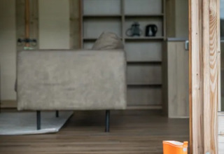 Interno del lodge Wellness Luxe a Landrijk de Reesprong con divano, pavimento in legno e stivale arancione.