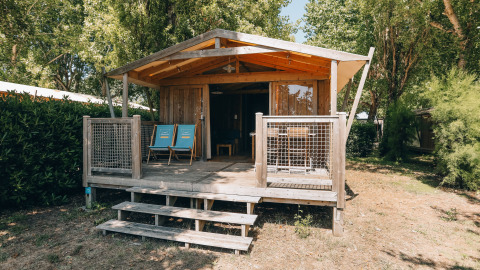 Wooden cabin with veranda and blue chairs at Lodge Premium, Campsite Seasonova Ile de Ré, France, in nature.