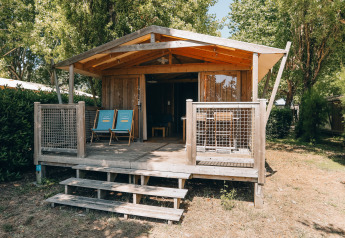 Wooden cabin with veranda and blue chairs at Lodge Premium, Campsite Seasonova Ile de Ré, France, in nature.