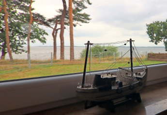 Modelschip op vensterbank met uitzicht op strand en bomen bij lodge Am Strand in Duitsland.