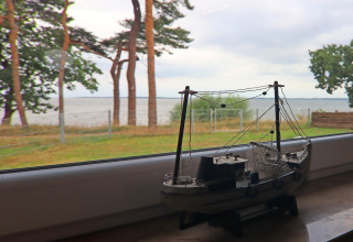 Modelschip op vensterbank met uitzicht op strand en bomen bij lodge Am Strand in Duitsland.