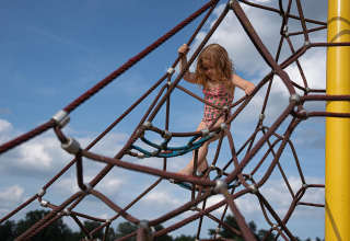 Ein Kind klettert auf einem Klettergerüst aus Seilen im Arden Parks Tulderheyde, Antwerpen, Belgien.