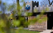 Holzlodge Kasteel Uylenburght im Camping de Zandstuve, Niederlande, mit grünen Blättern im Vordergrund.