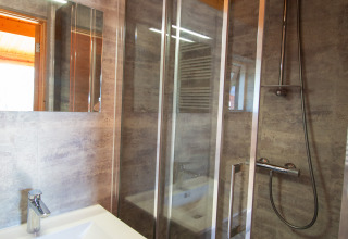 Modern bathroom in a chalet at Campsite Mareveld in the Netherlands, featuring a shower and washbasin with mirror.