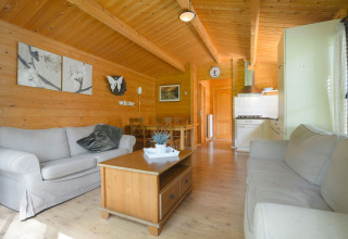 Wooden interior of a Chalet at Campsite Mareveld in the Netherlands with sofas and a small kitchen.