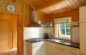 Keuken in chalet op Camping Mareveld in Nederland met houten interieur, raam, servies en fornuis.